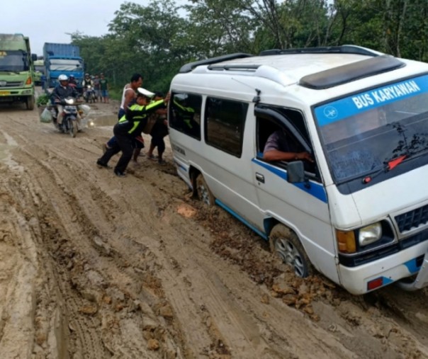 Petugas Kepolisian bersama warga, berusaha membantu kendaraan yang terjebak di Jalan Lintas Perawang, Kabupaten Siak. Foto: hadi 