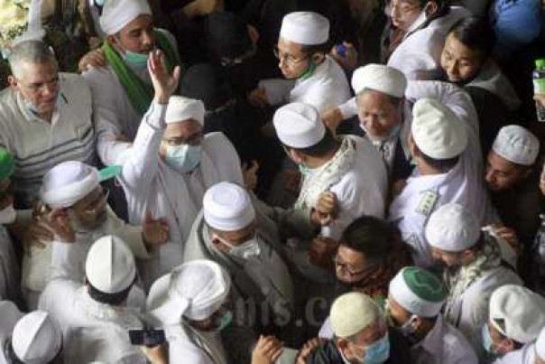 Habib Rizieq Shihab melambaikan tangan kepada ribuan pendukungnya saat tiba di Bandara Internasional Soekarno Hatta, Selasa pagi dari Arab Saudi. 